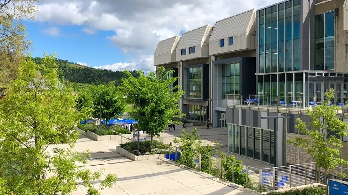 Cement and class building with green mountains in the background.