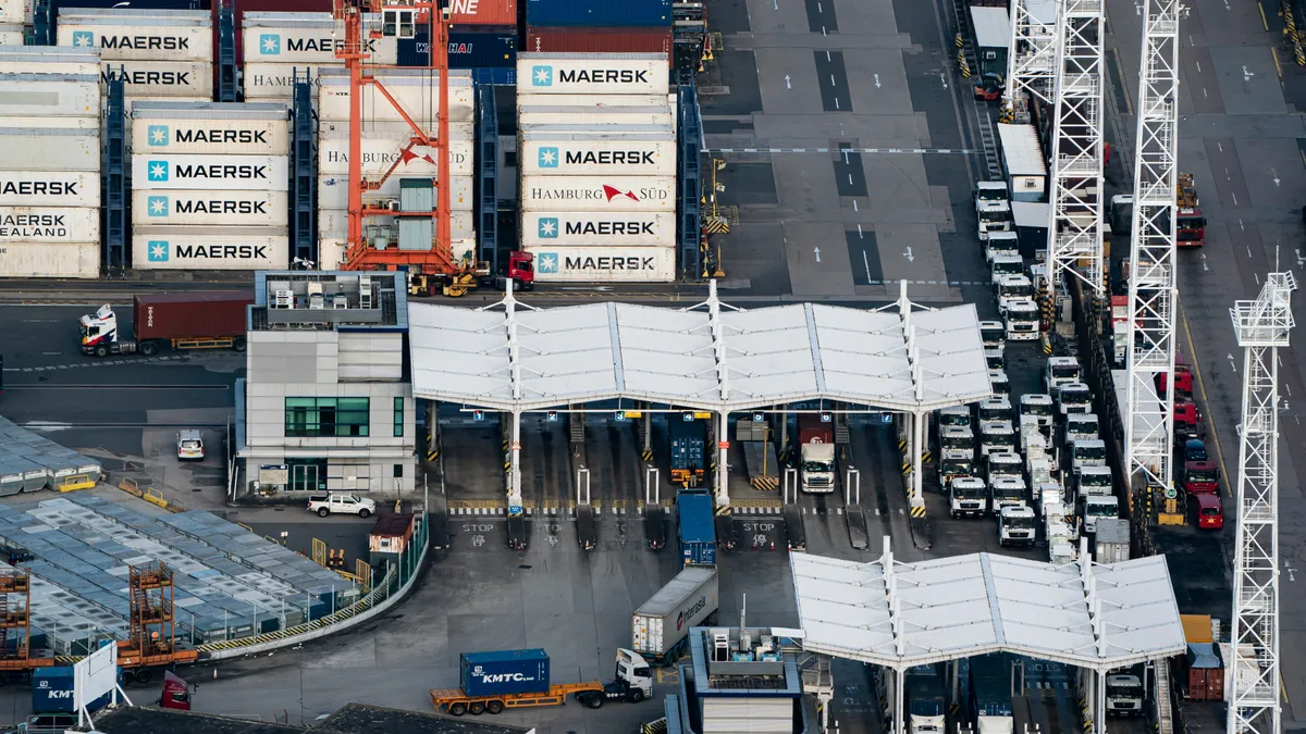 Trucks transporting shipping containers travel between stacked containers at Kwai Tsing Container Terminal on November 10, 2021 in Hong Kong, China.