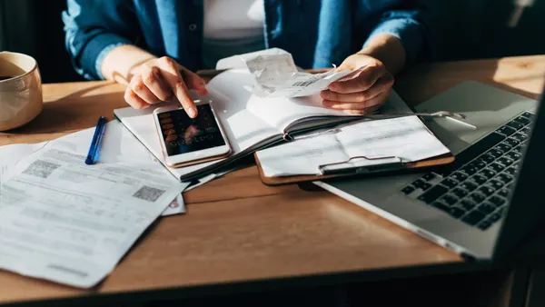 Woman accountant use calculator and computer with holding pen on
