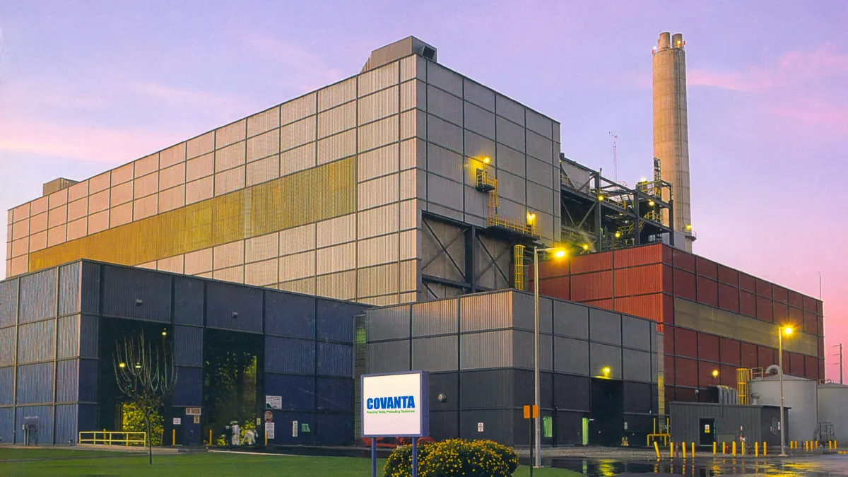 An industrial facility pictured in the evening with a smokestack in the back and a 'Covanta' sign at front