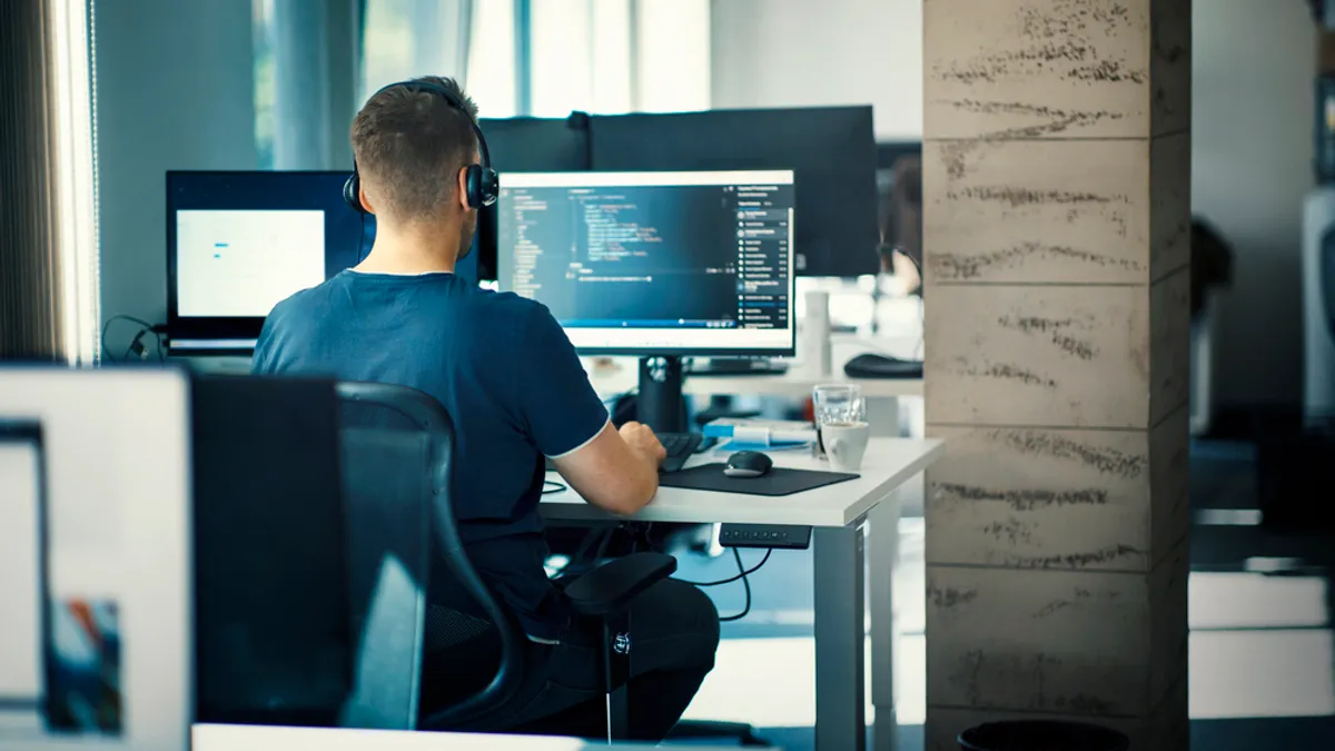 a tech worker sits in front of a terminal in a brightly lit office