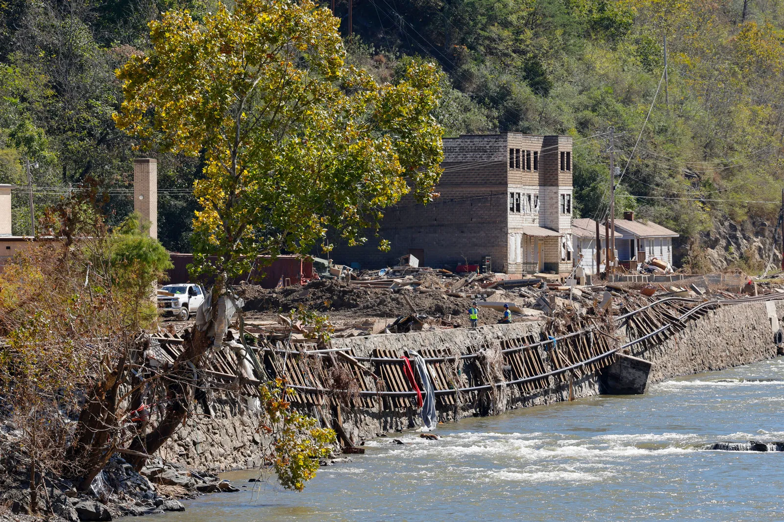 Train tracks have fallen over the side of a river bank after a flood.