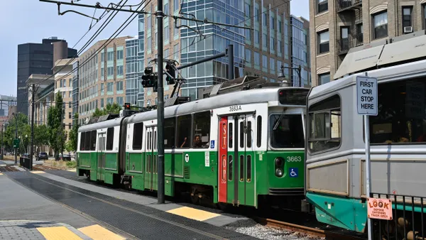 Green light rail train crossing a roadway.