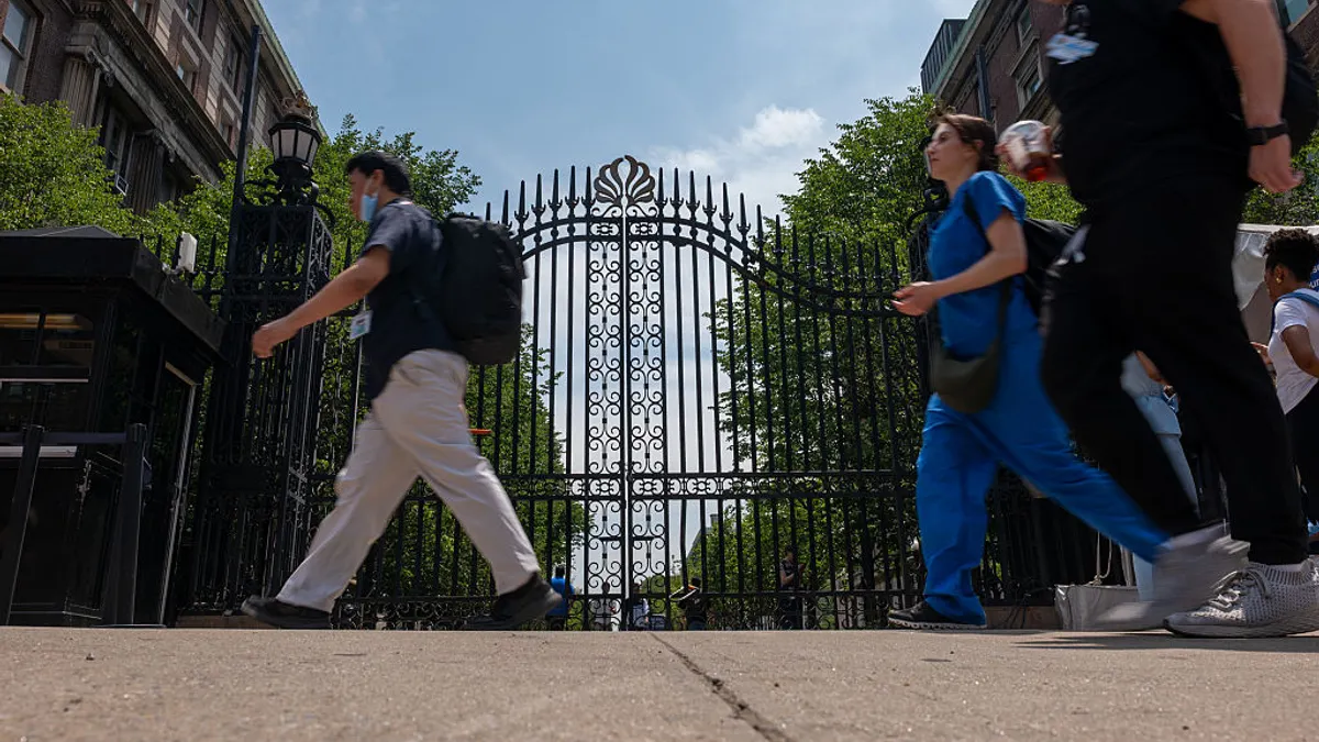 A few pedestrians walk by Columbia University's gates.