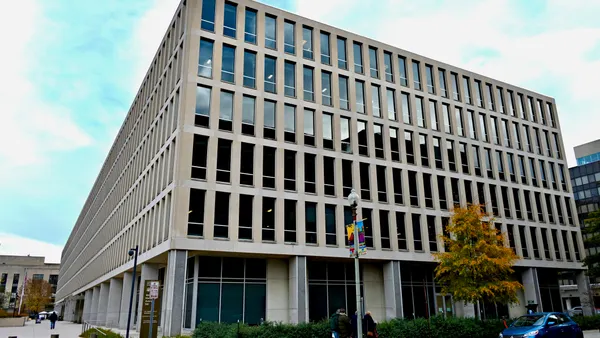 The outside of a building is seen. The building is concrete and has many windows