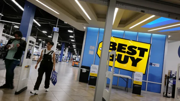 Two shoppers leave a Best Buy store.