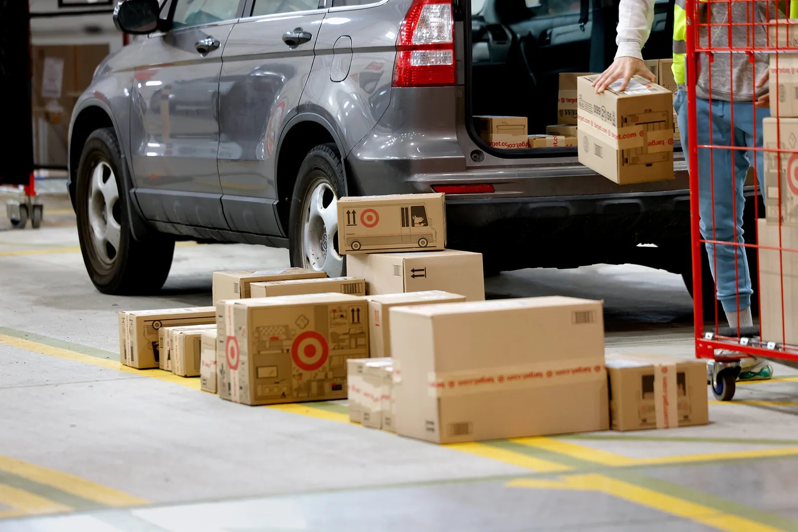 Packages with the Target logo are loaded into a vehicle by a person.