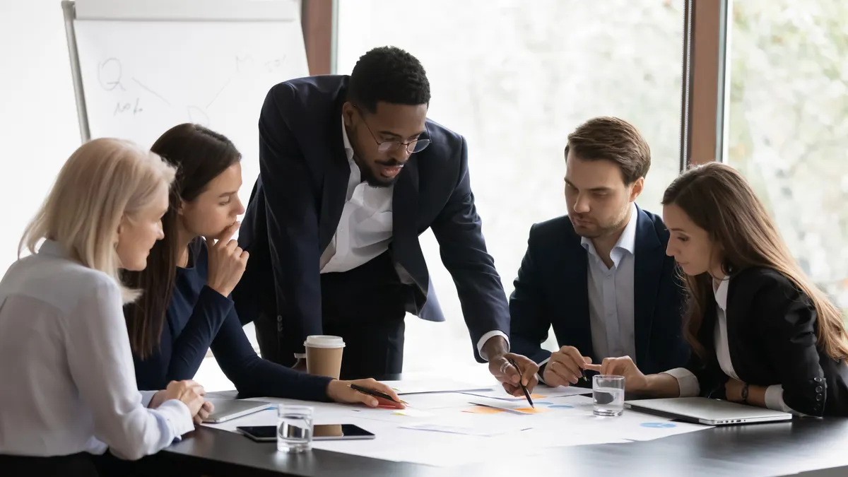 Confident african American male boss work cooperate with diverse team at office briefing