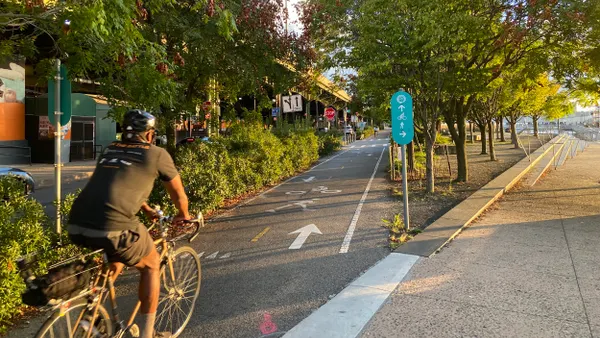 A short-sleeved bicyclist on a bike part surrounded by trees.
