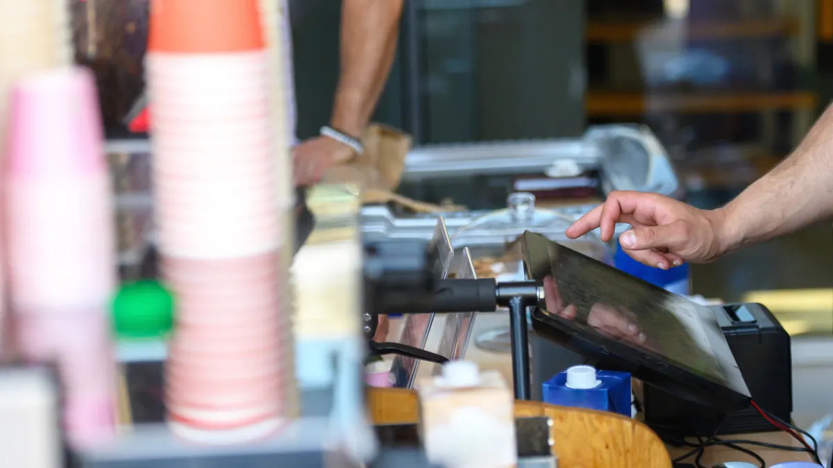 Coffee shop business owner standing at the cashier while working