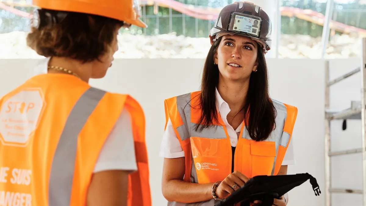 Two women in construction talking to each other.