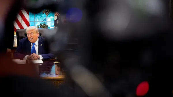 President Donald Trump sitting at his desk in the Oval Office.