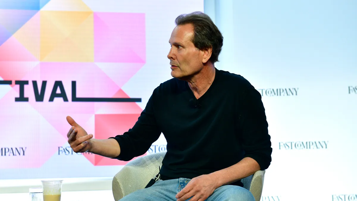 PayPal CEO Dan Schulman sitting and gesturing with his hand.