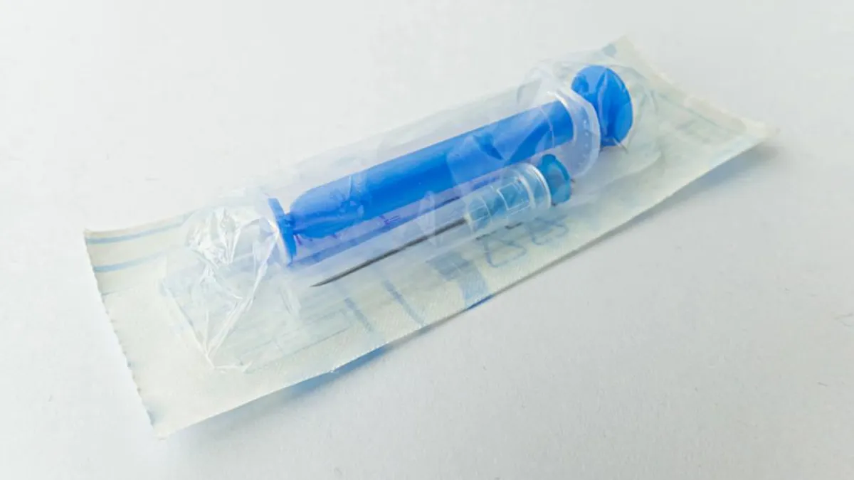 A syringe with a separate needle are in plastic packaging.