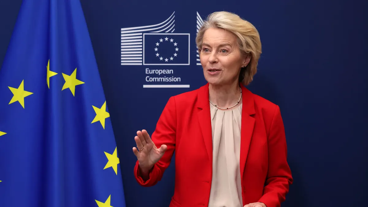 European Commission President Ursula von der Leyen speaks in front a European Union flag.