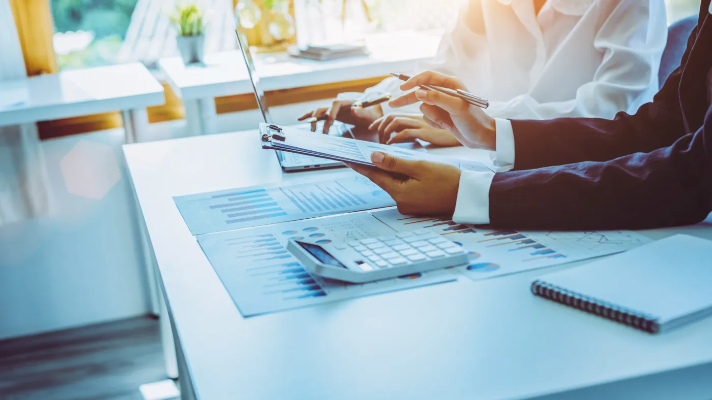 Close-up of two business people calculating financial statements at a desk.