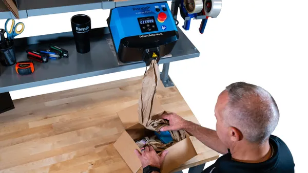 A person adds void fill to a box package using Ranpak's FillPak Mini void fill converter