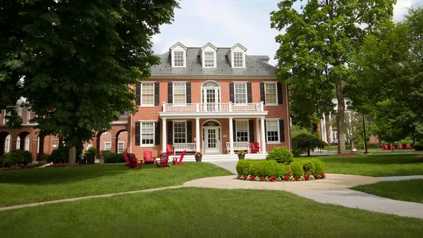 Red brick building with white columns and dormer windows.