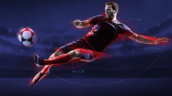 a man jumping up to kick a soccer ball in a stadium