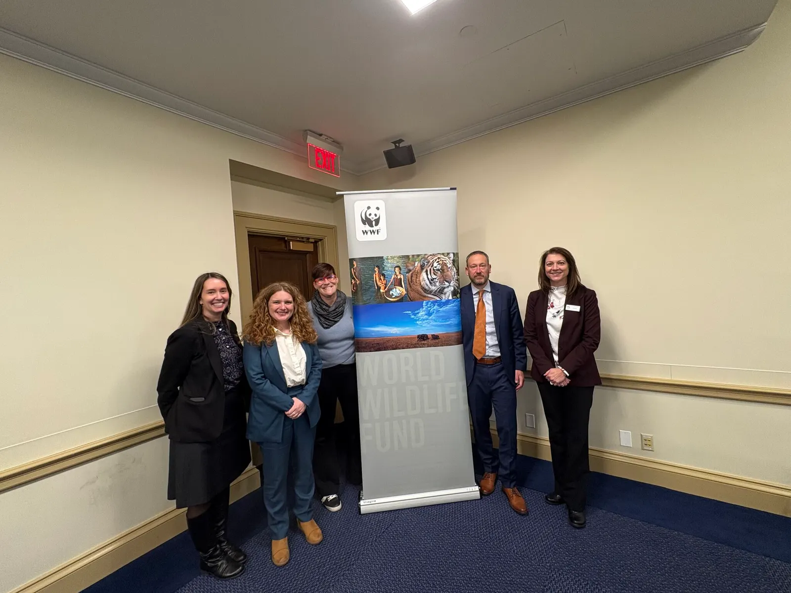 Participants in a House Oceans Caucus briefing about federal EPR stand around a WWF banner.