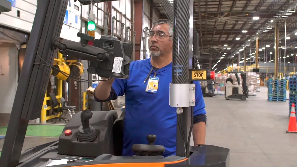 A warehouse forklift operator uses an autonomous forklift inside a distribution center.