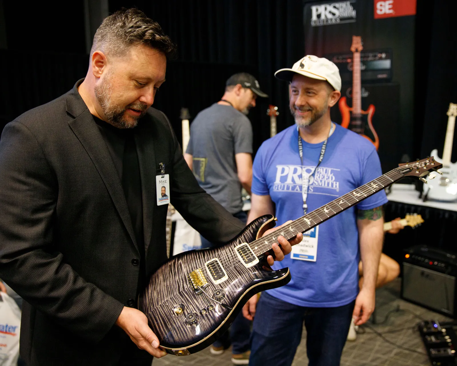 Two people admire an electric guitar at a music retail event.