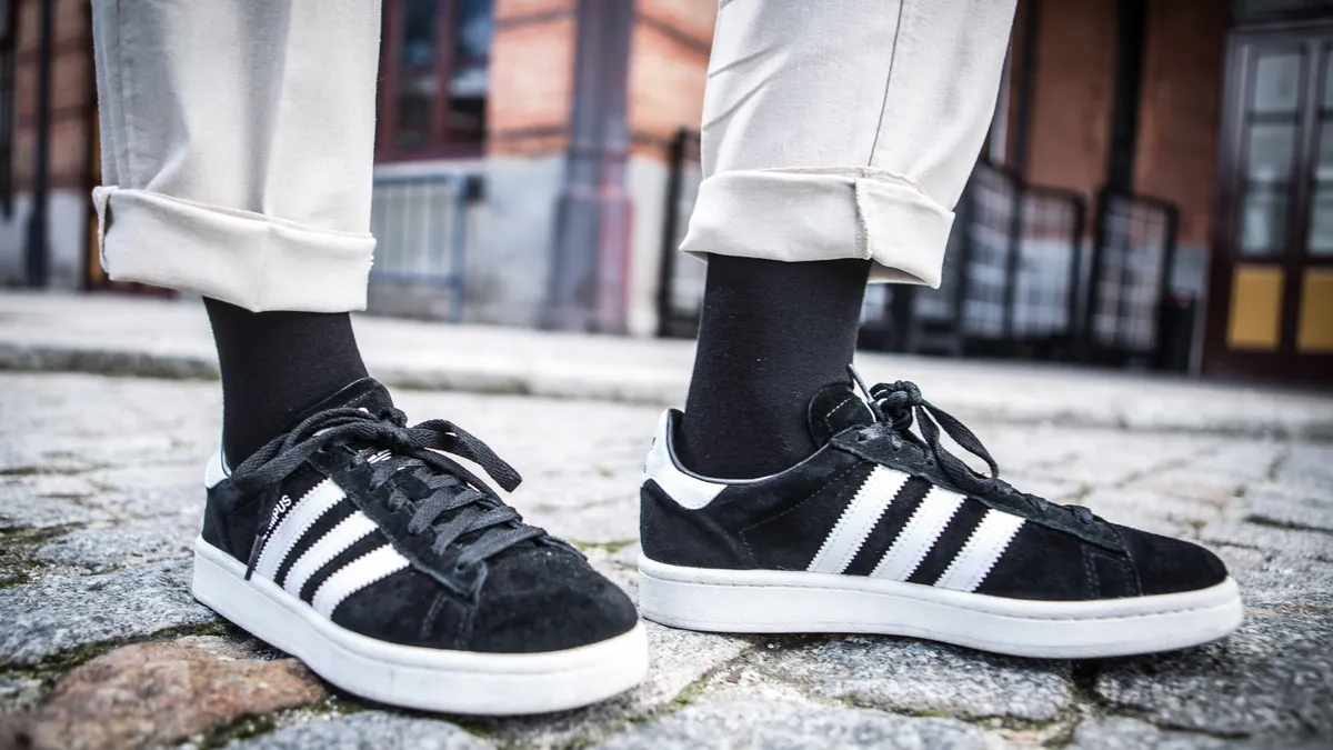 A closeup of a person's shoes, black Adidas sneakers.