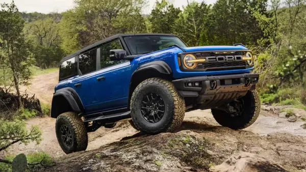 A blue 2025 Ford Bronco SUV driving over rocky terrain.