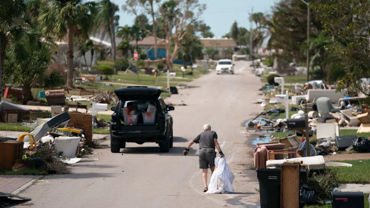 A person drags debris through a residential street in Florida affected by a recent hurricane