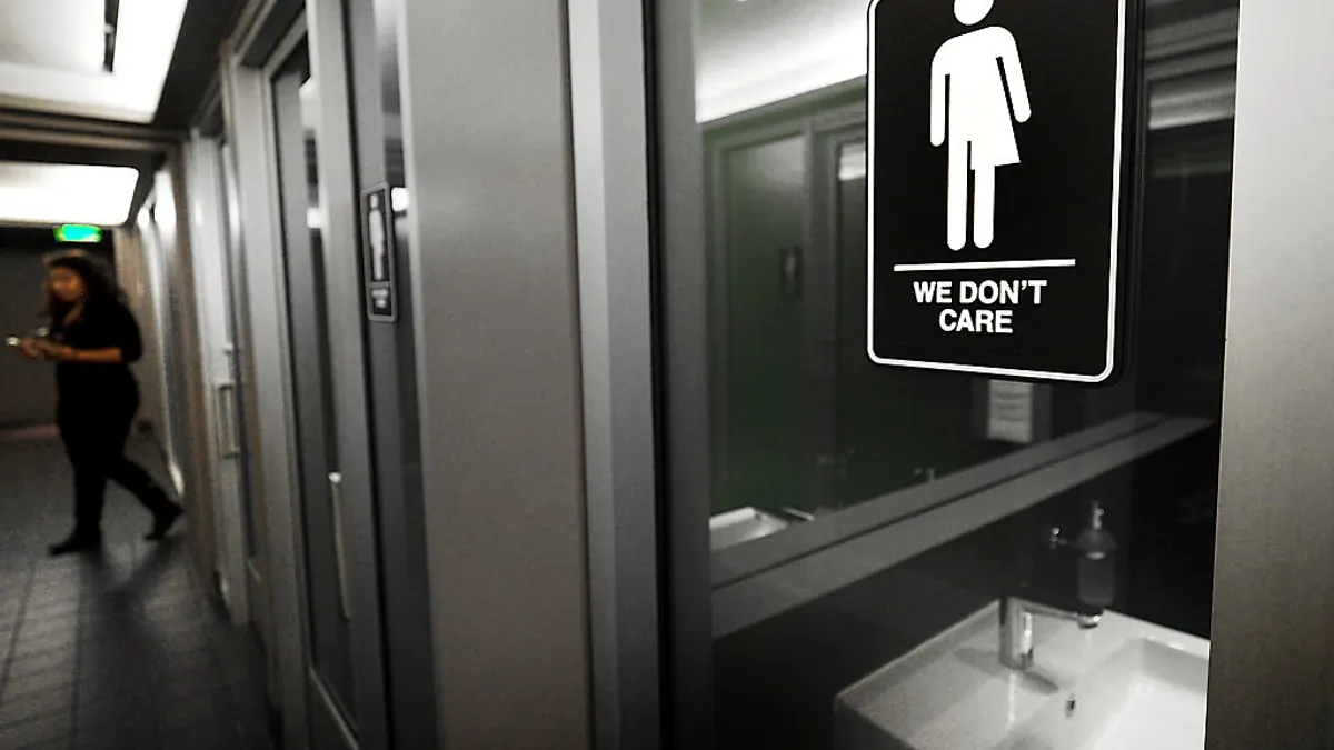 Door to gender-neutral restroom with sign reading "We Don't Care"