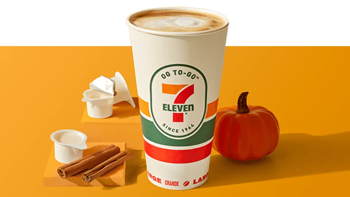 A photo of a cut of coffee with the 7-Eleven logo on it. Empty creamer packets are on the surface around the cup.