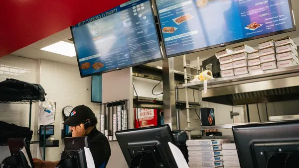 A Domino's Pizza employee assists a customer over the phone.