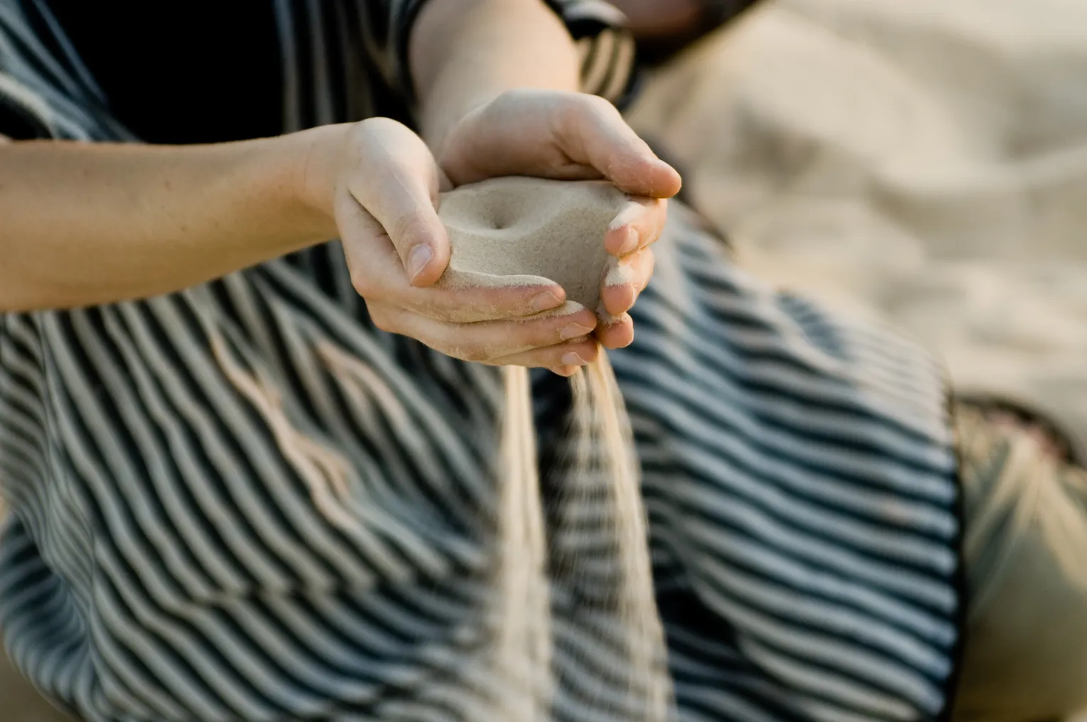 Sand slipping through hands cupped together.