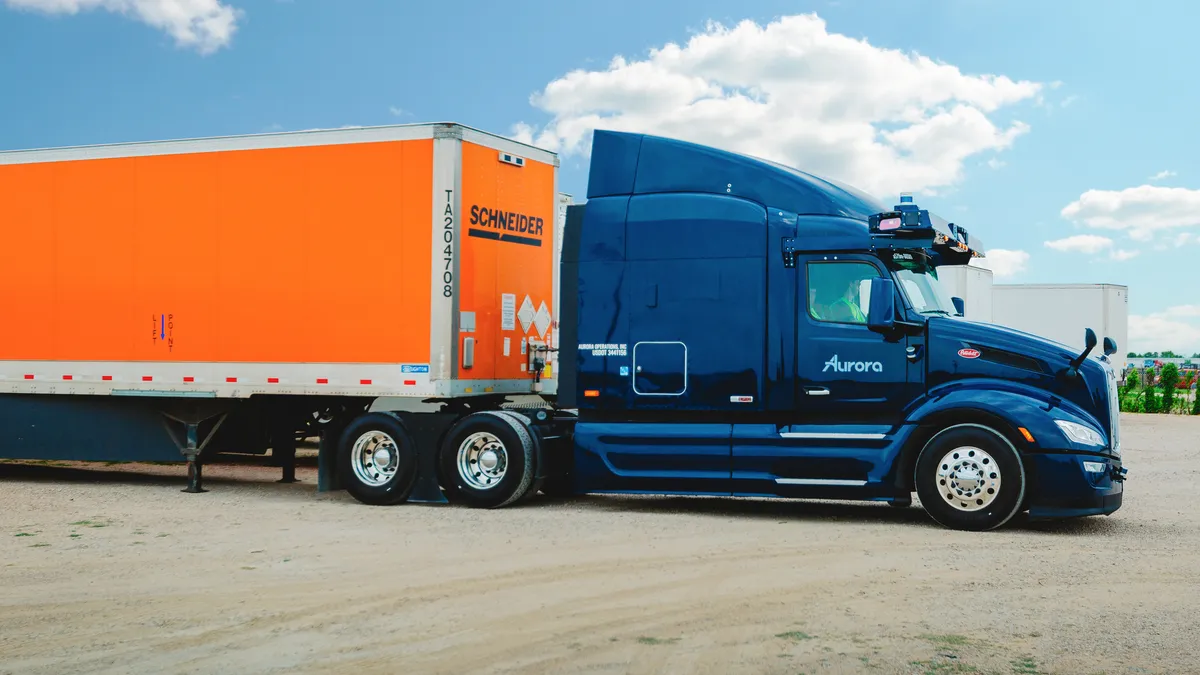 An Aurora truck carrying a Schneider trailer