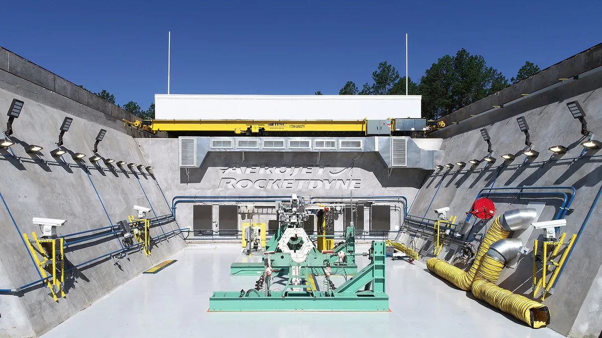 A greenish test bay at Aerojet Rocketdyne's gray and white manufacturing facility in Camden, Arkansas on a sunny and clear day.