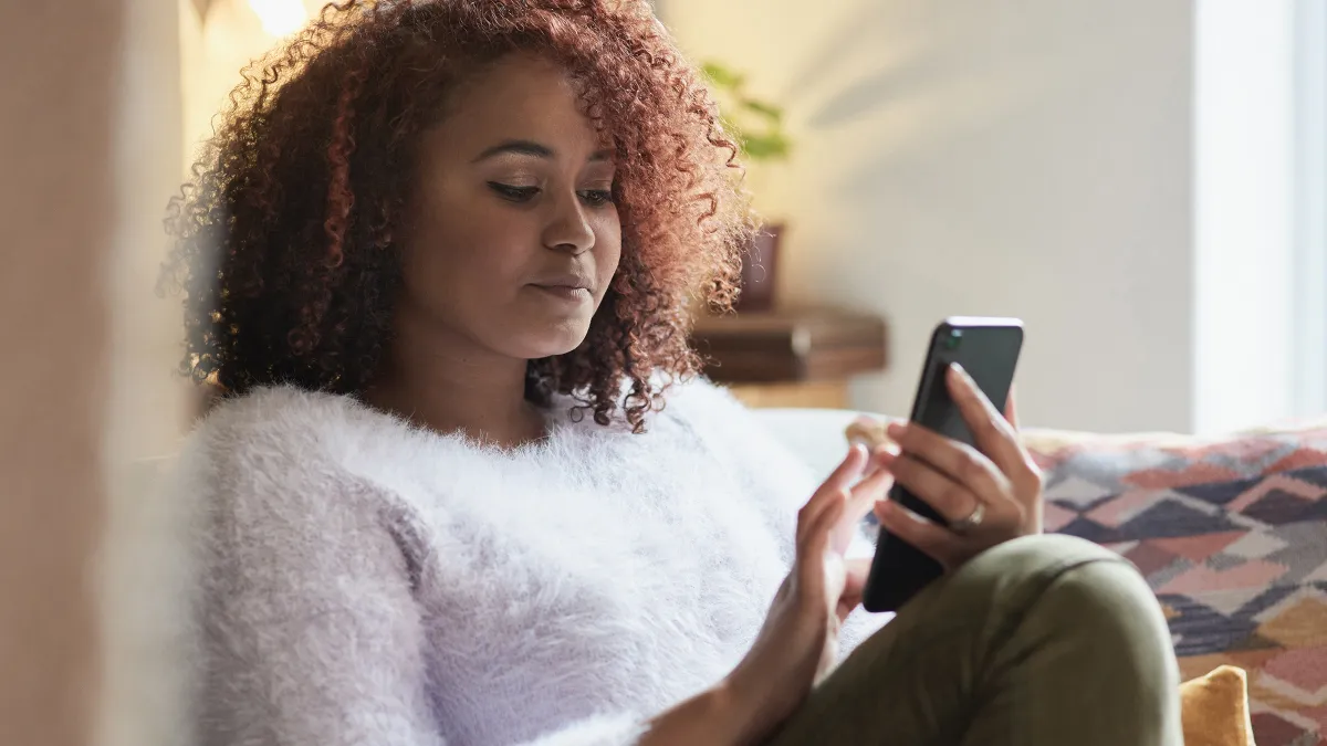 Shot of a young woman using a cellphone while relaxing at home