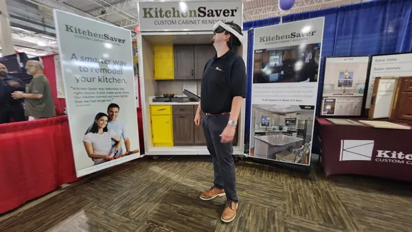 a man stands in an expo booth with a VR headset on