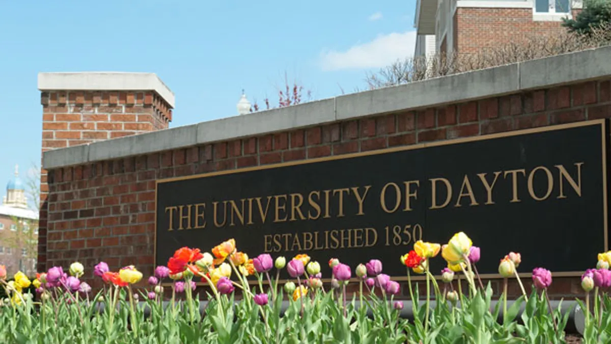 A brownstone welcome sign, large and stone. It reads, "The University of Dayton, Established 1850."