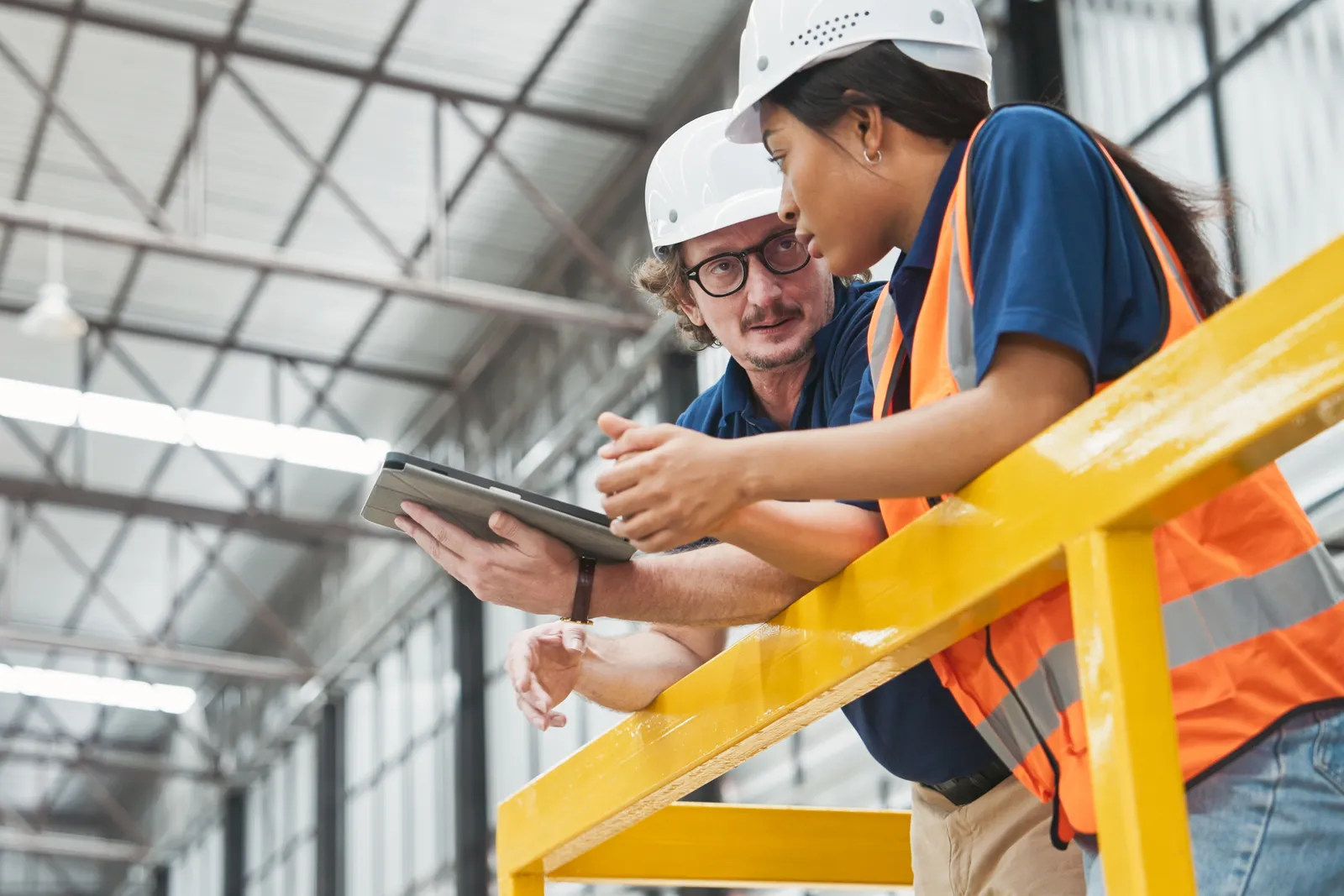 Two technicians look at a tablet in a facility.