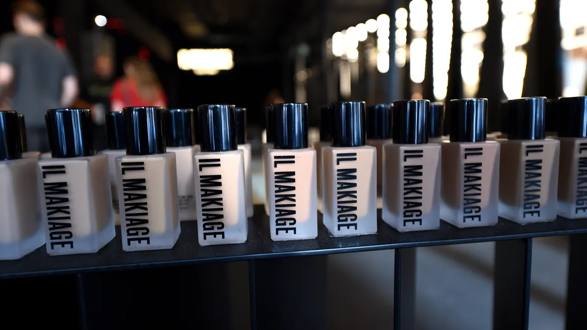 A display of Il Makiage makeup bottles in clear glass with black lids