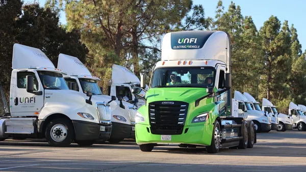 A green and white semitruck with the words "UNFI electric vehicle" above the cab.