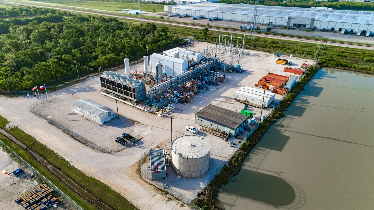 A sky view of a power plant, lit by the sun. The plant sprawls across a large space.