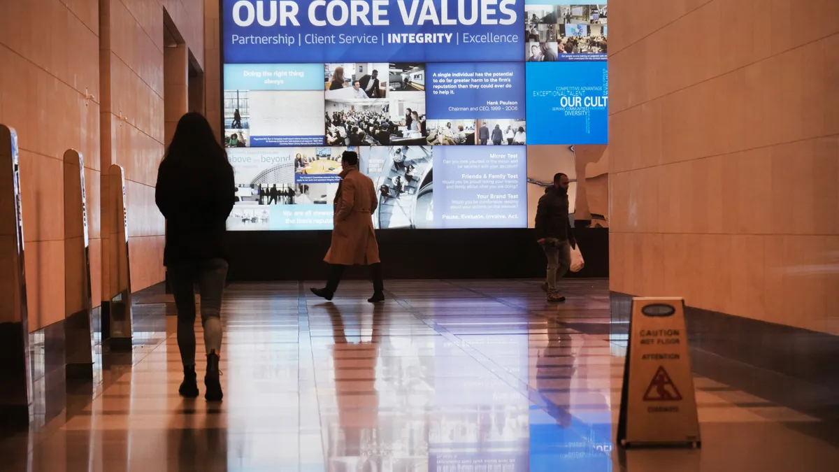 People are seen walking through an office building lobby.