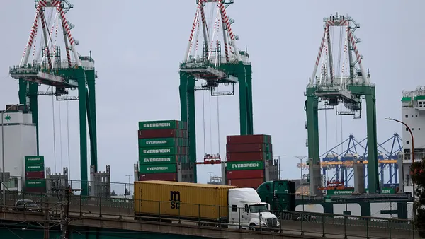 A truck drives over a bridge near a water port.