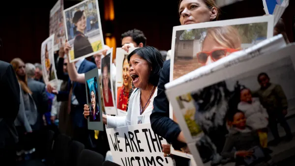 A group of peoplle holding up signs and photos of their deceased love ones.