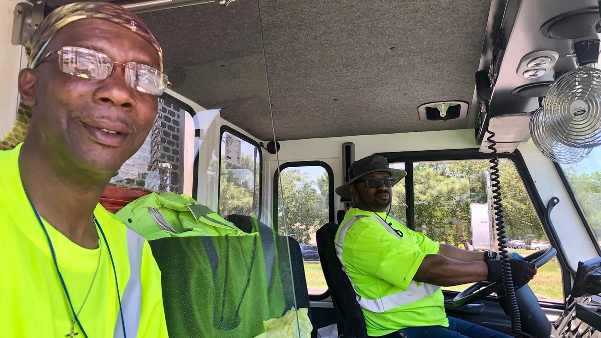 Employees riding with protective partition in Charlotte Solid Waste Services collection truck