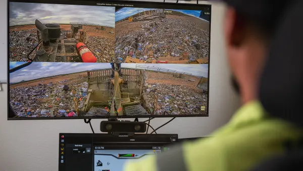 An operator looks at multiple computer screens that show landfill operations.