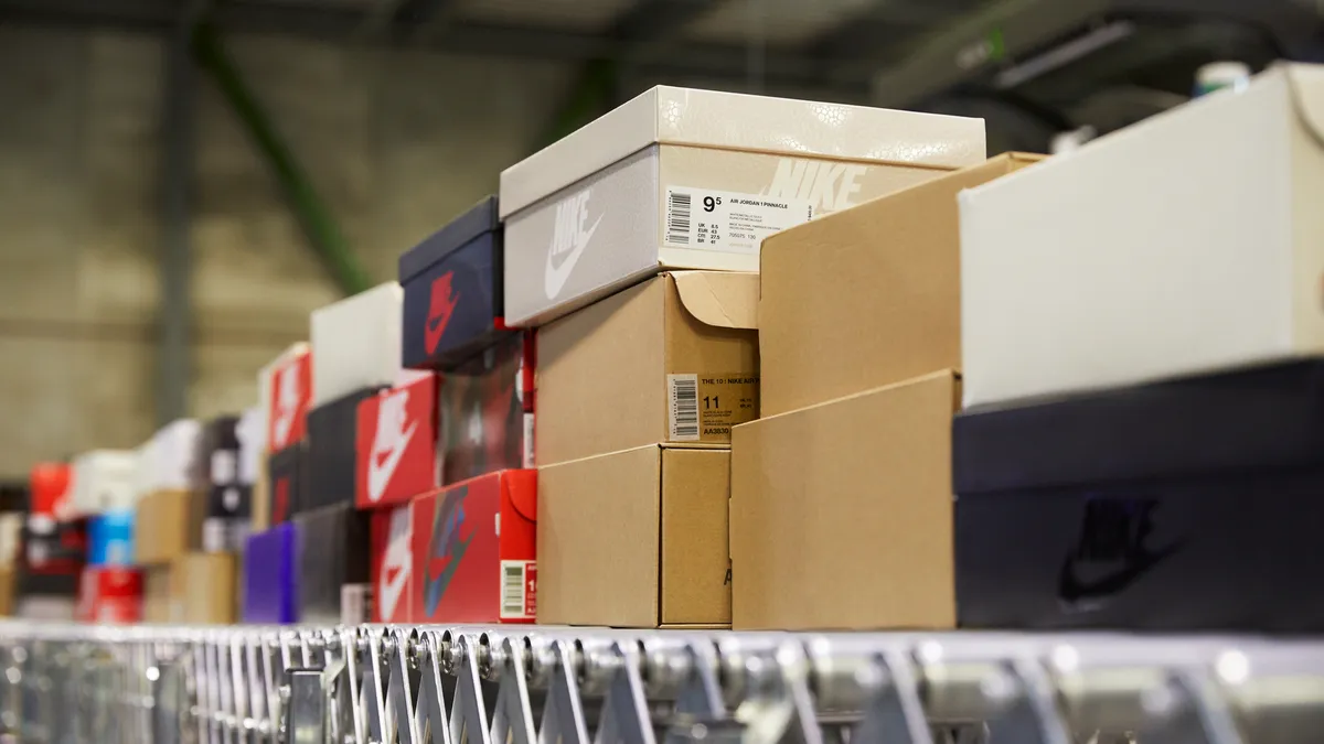 Shoe boxes stacked on a wire shelf in a warehouse.