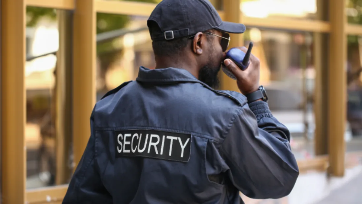 Man wearing a security vest and talking on walkie talkie