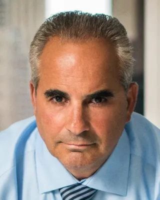 Man in blue shirt and grey hair.